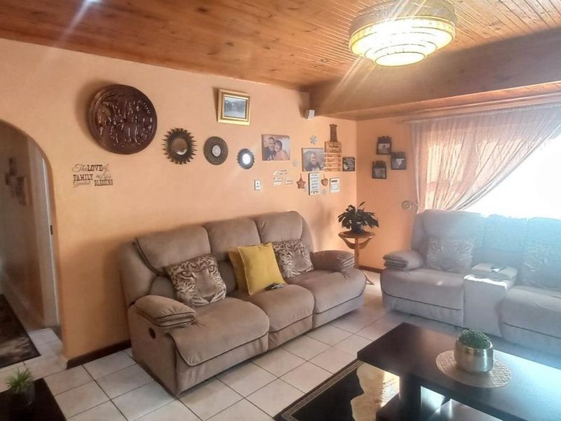A living room featuring a timber-clad ceiling, ceramic floor tiles, and a central flush mount light fixture.