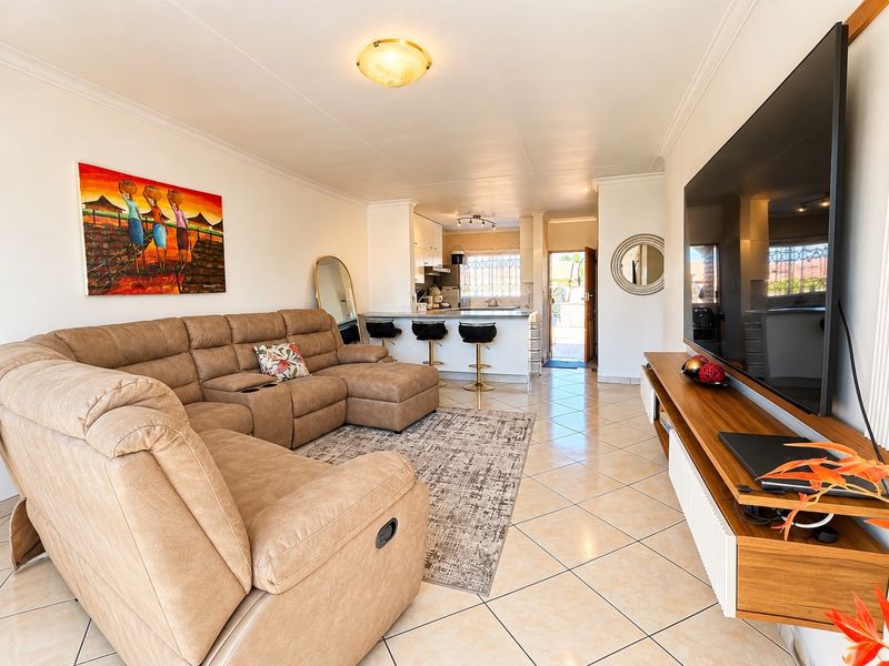 An open-plan living area featuring ceramic tile flooring, a breakfast bar, and a seamless transition into the kitchen space.