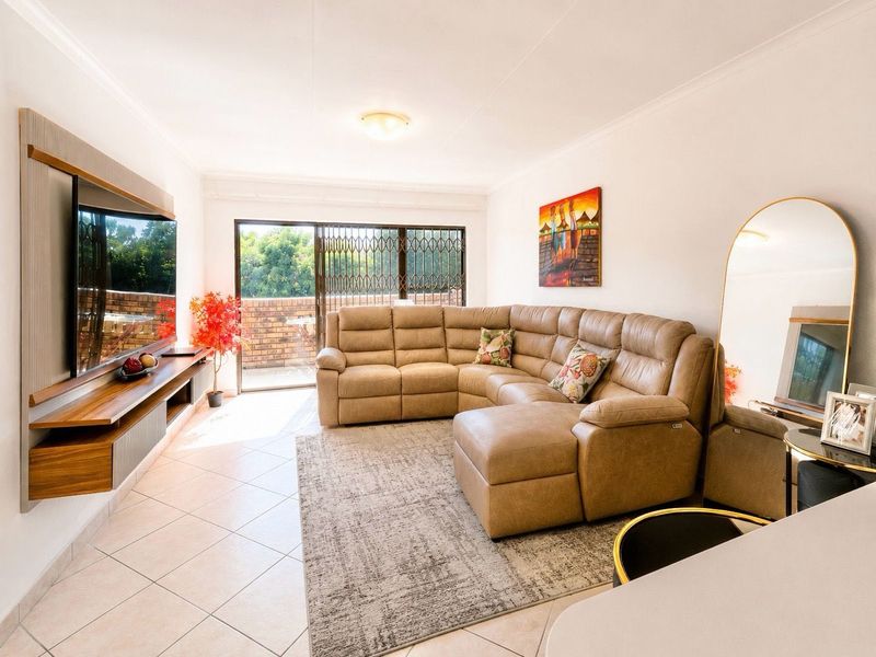 A bright living room featuring tiled flooring, a floating media console, and a sliding glass door leading to an outdoor balcony area.