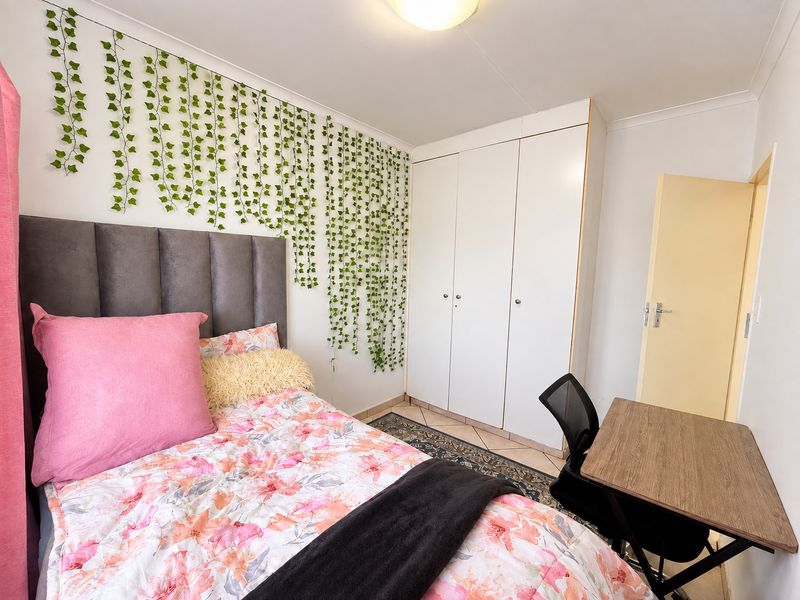 A bedroom featuring built-in cupboards, tiled flooring, and coved ceiling details, providing a functional space with neutral finishes.