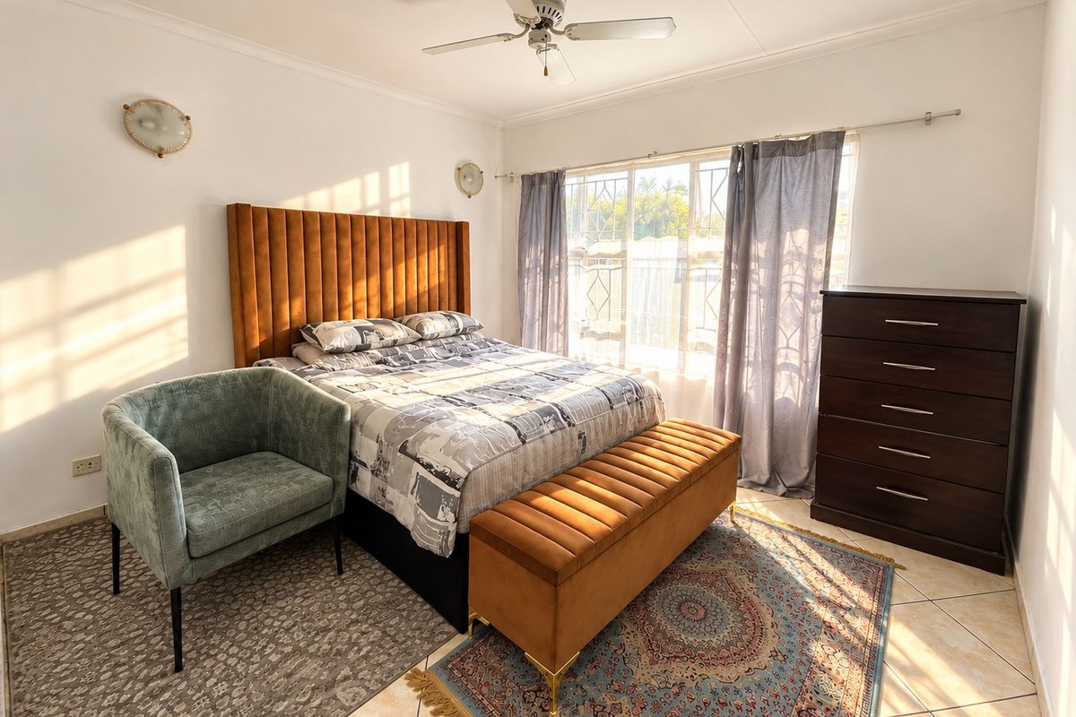 A well-lit bedroom featuring tiled flooring, a ceiling fan, wall sconces, and a security gate over the window.