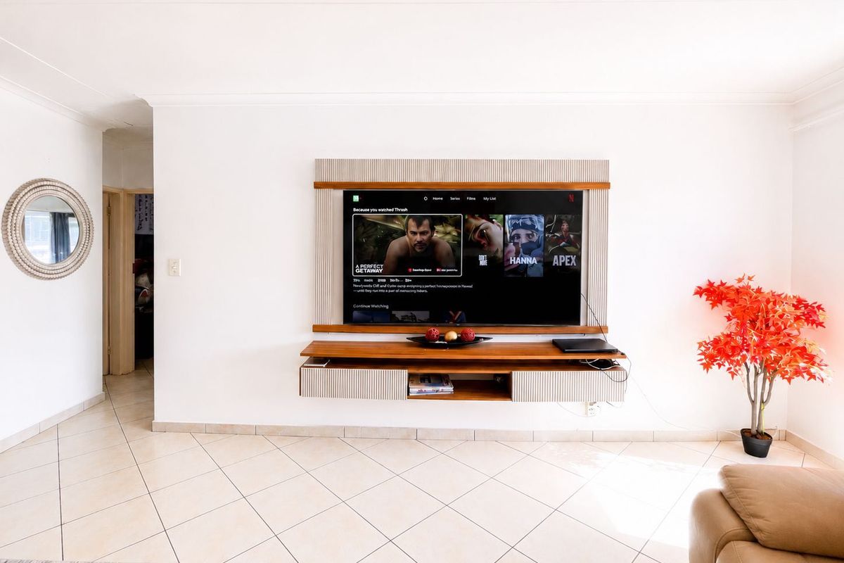 A well-maintained living room featuring a custom built-in media console and neutral tiled flooring, providing a clean and functional entertainment space.