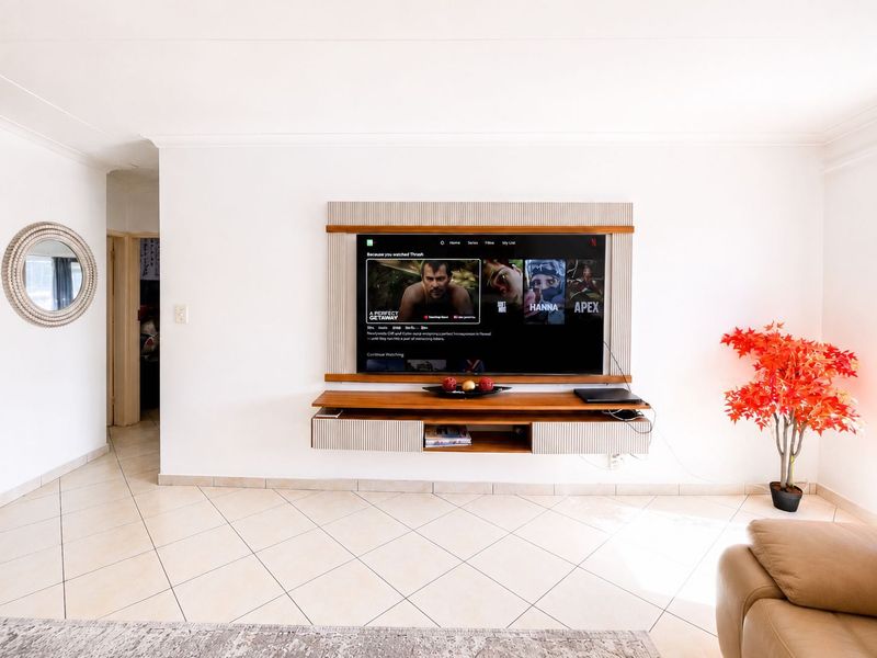 A well-maintained living room featuring a custom built-in media console and neutral tiled flooring, providing a clean and functional entertainment space.