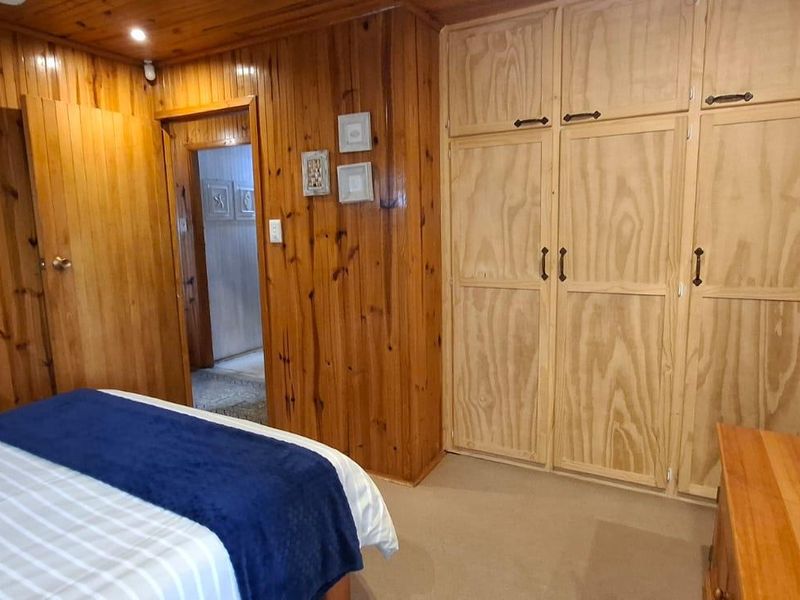 Bedroom featuring extensive timber wall and ceiling paneling, complemented by built-in timber wardrobe cabinetry and recessed lighting.