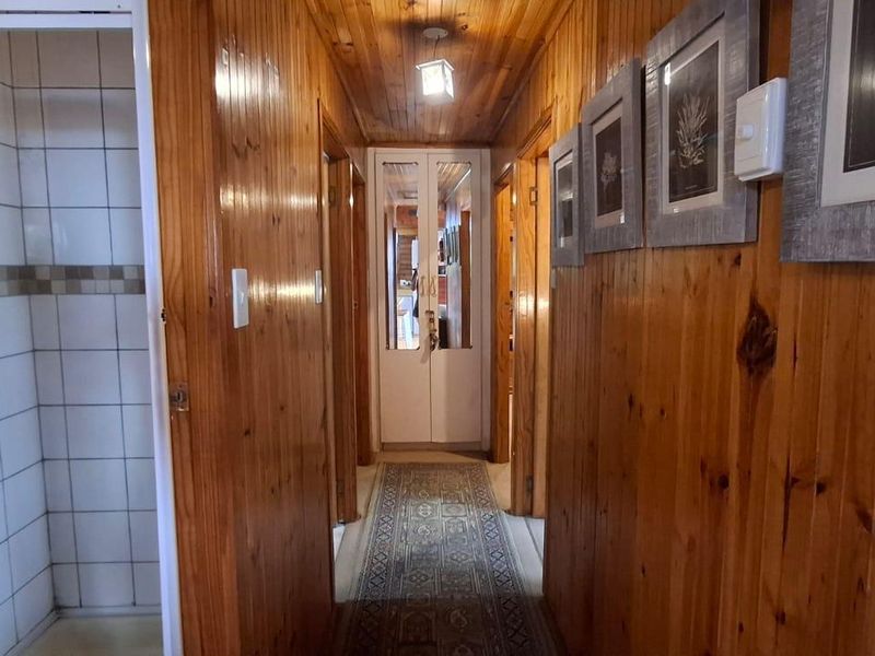 A hallway featuring extensive timber wall and ceiling paneling, leading to a tiled shower cubicle.