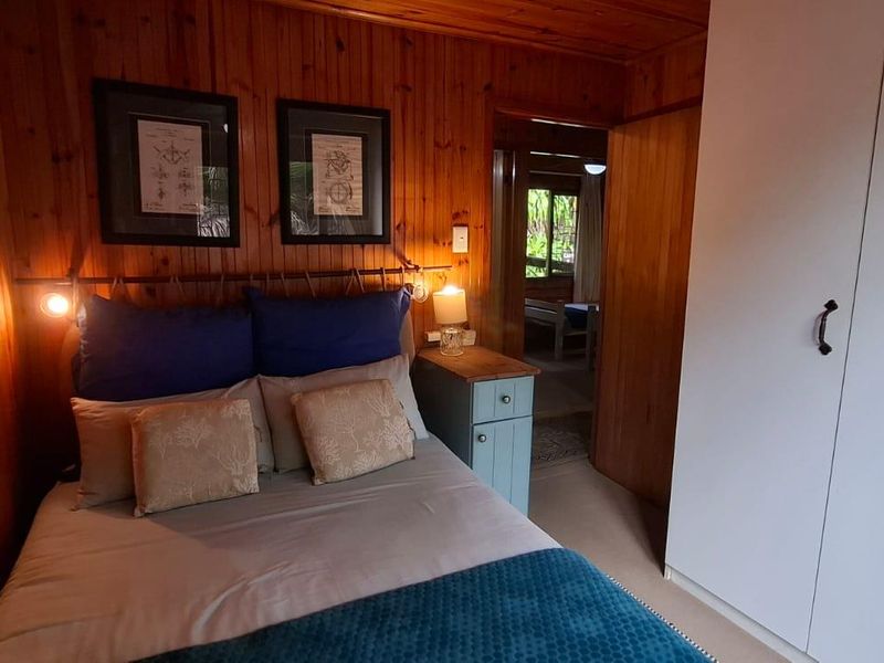 A cozy bedroom featuring warm timber wall paneling, a timber ceiling, and a built-in wardrobe with white doors.