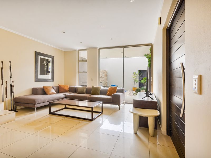 Spacious living room featuring polished tile flooring, recessed lighting, and large sliding glass doors providing seamless access to the outdoor patio area.