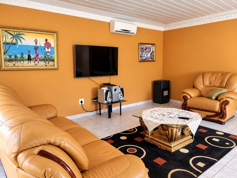 A living room featuring tiled flooring, crown molding, and a tongue and groove ceiling, equipped with a wall-mounted air conditioning unit.