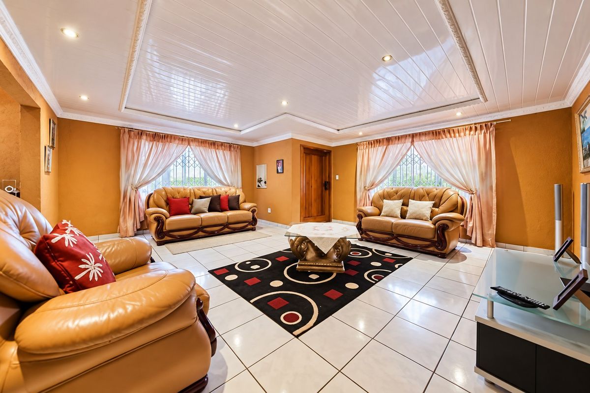 A spacious living room featuring tiled flooring, recessed ceiling lighting, and security bars on the windows.