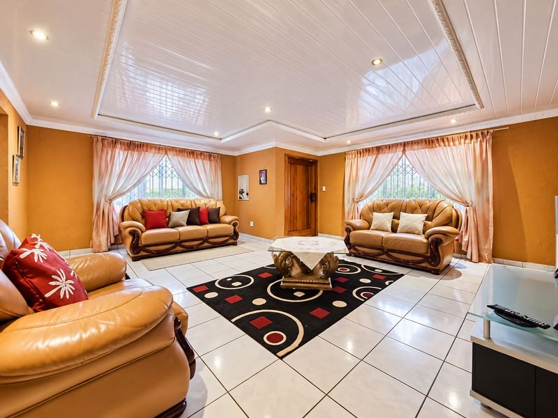 A spacious living room featuring tiled flooring, recessed ceiling lighting, and security bars on the windows.