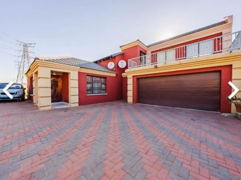 Front elevation of a two-story house featuring a double garage, paved driveway, and an upper-level balcony.
