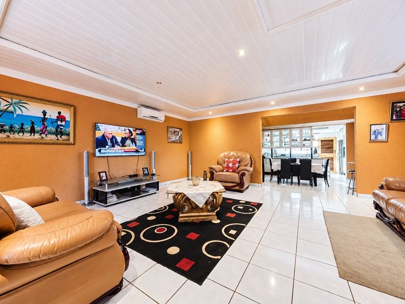 Spacious open-plan living and dining area featuring tiled floors, recessed lighting, and a split-system air conditioner, with a connected dining space.