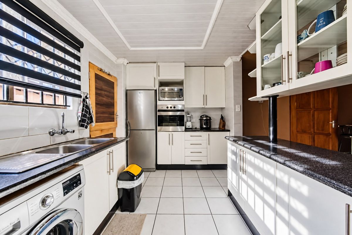 A functional kitchen featuring white cabinetry, granite countertops, built-in oven and microwave, double sink, and tiled flooring with a classic tongue and groove ceiling.