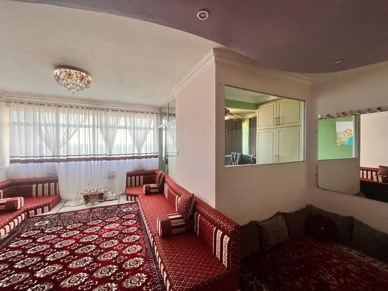 A living room featuring decorative ceiling molding, a crystal chandelier, and an interior glass partition window looking into an adjacent space.
