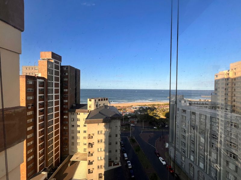 An elevated urban view looking out over surrounding apartment buildings towards the coastline and ocean.