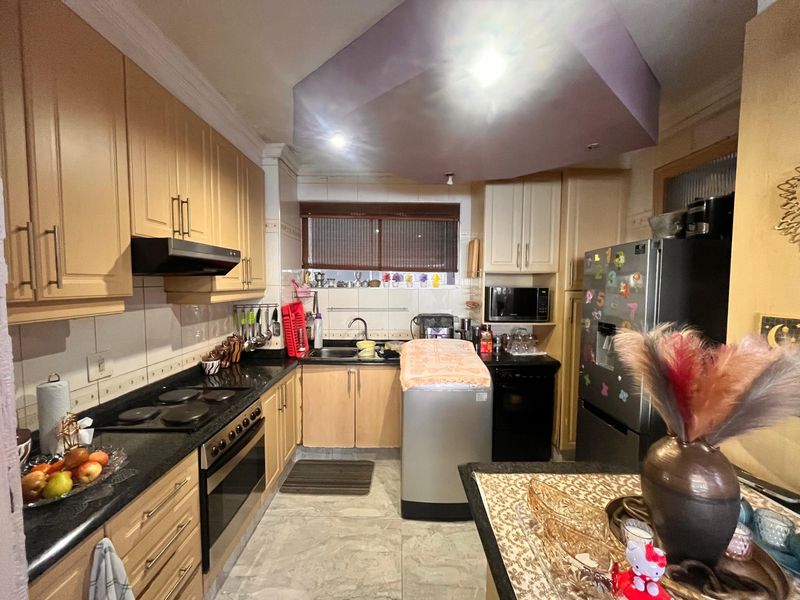 A functional kitchen featuring light wood cabinetry, granite countertops, integrated oven and hob, and a tiled backsplash with recessed lighting.