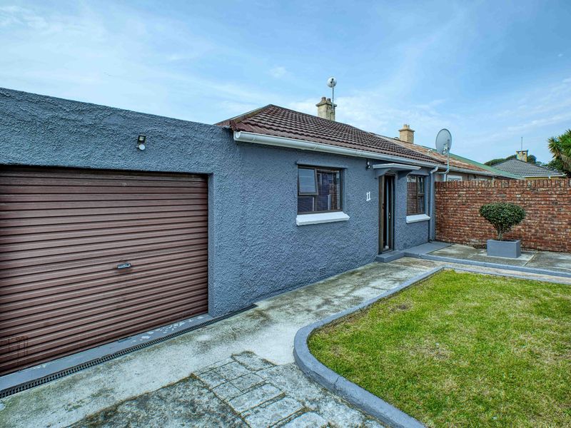 Front exterior view of the property featuring a single garage with a roller door, concrete driveway, and a small front garden area.
