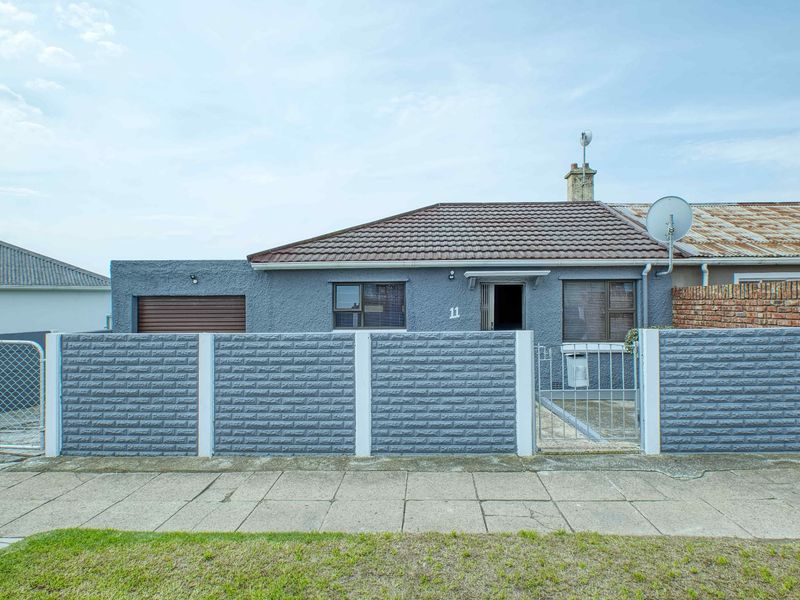 Front elevation of a single-story house featuring a tiled roof, grey textured facade, integrated garage, and a secure precast concrete boundary wall.