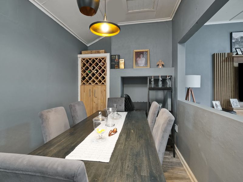A well-maintained dining room featuring a built-in wine rack, modern pendant lighting, and durable laminate flooring, creating a cozy and functional space.