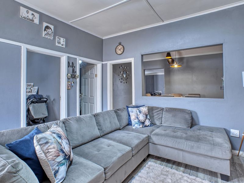 A living room featuring laminate flooring, a pass-through window to the adjacent space, and multiple interior panel doors.