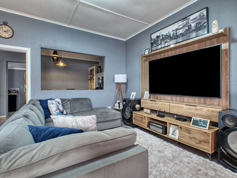 A comfortable living room featuring a custom built-in media unit and a convenient pass-through window connecting to the adjacent space.