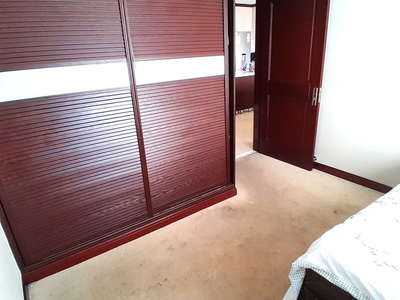 Bedroom featuring a large built-in sliding door wardrobe and carpet flooring, with an open doorway leading to an adjacent room.