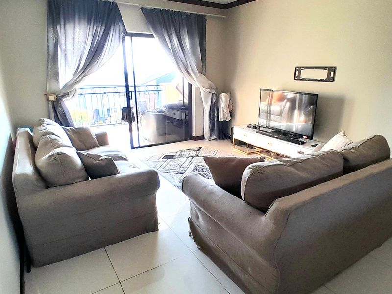 A living room featuring tiled flooring, crown molding, and a sliding glass door providing access to an outdoor balcony area.