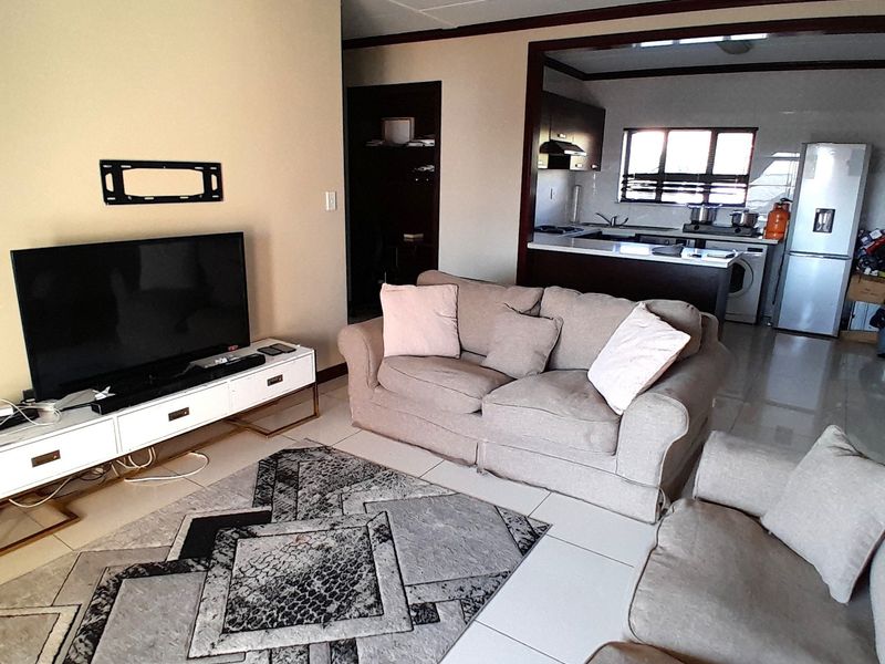 Open plan living area featuring tiled floors and a connected kitchen with built-in cabinetry and counter space.