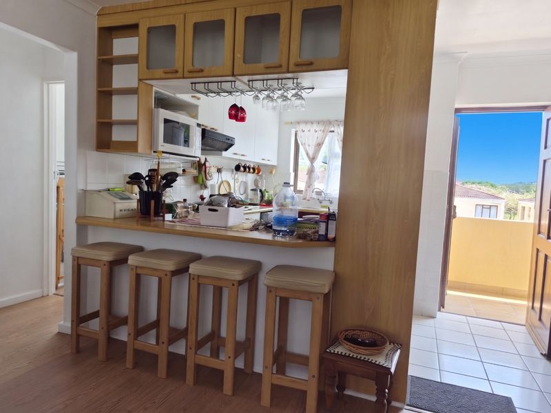 A functional kitchen featuring a breakfast bar, built-in cabinetry, and integrated appliances, with direct access to an outdoor balcony area.
