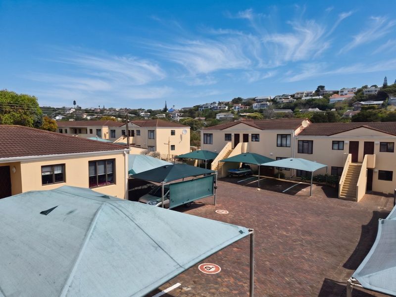 An elevated view of the apartment complex courtyard featuring paved parking areas with shade-cloth carports and multi-level residential building blocks.