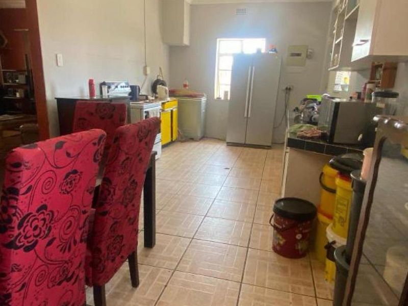 A functional kitchen space featuring tiled flooring and built-in cabinetry, offering a practical layout that could benefit from modern cosmetic updates.