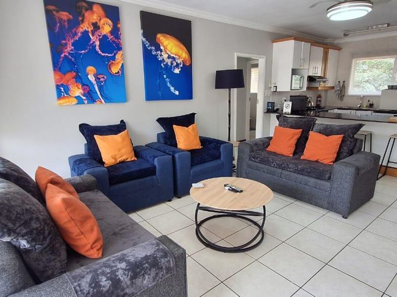Open-plan living area featuring tiled floors, a functional kitchen with granite countertops, and a sliding glass door leading to an outdoor space.