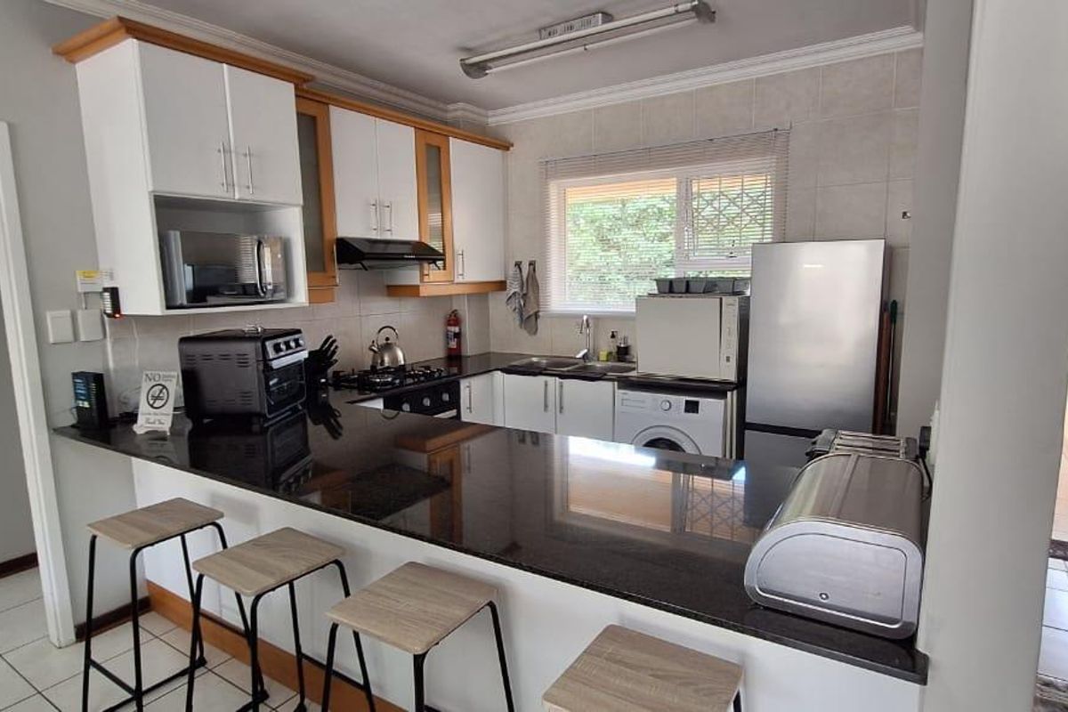 Functional kitchen featuring granite countertops, ample built-in cabinetry, a gas hob, and a convenient breakfast bar for casual dining.