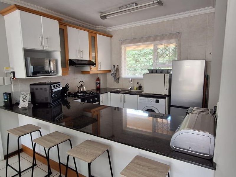Functional kitchen featuring granite countertops, ample built-in cabinetry, a gas hob, and a convenient breakfast bar for casual dining.
