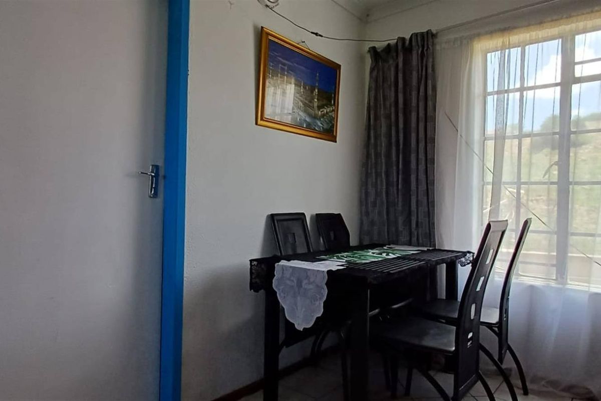 A living area featuring tiled flooring and a window with muntins, showing signs of wear on the door frame.