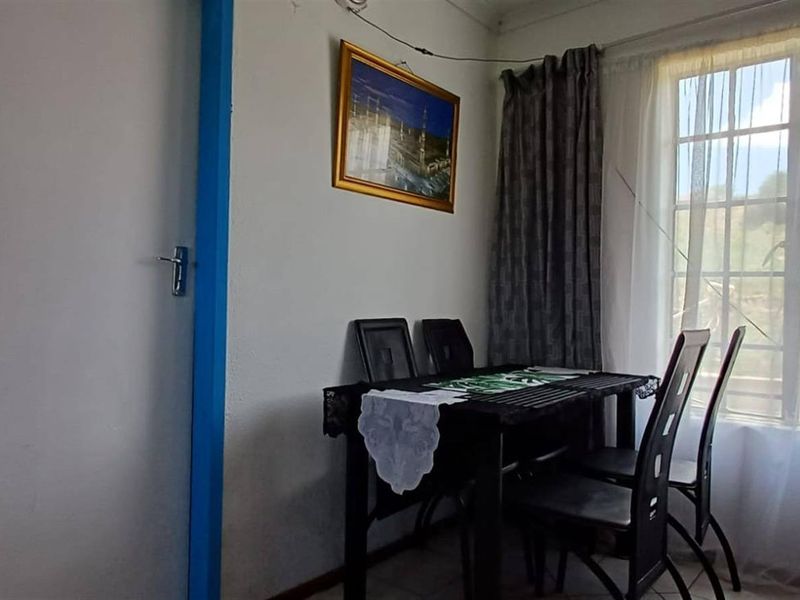 A living area featuring tiled flooring and a window with muntins, showing signs of wear on the door frame.