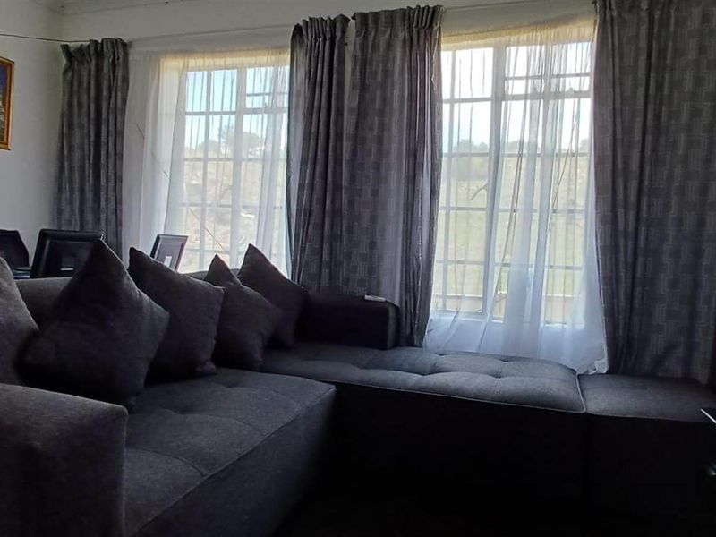 A living room featuring multi-pane windows with security bars and neutral wall finishes.
