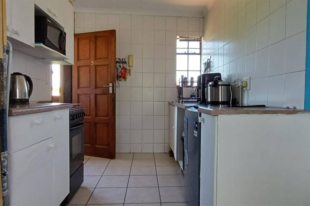 A functional kitchen featuring tiled walls and flooring, built-in cabinetry, and a freestanding stove, offering a practical layout for daily meal preparation.