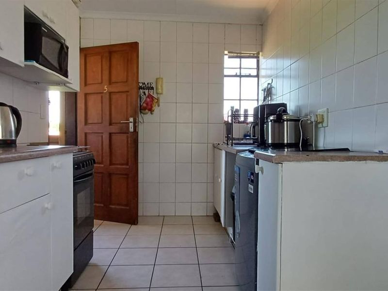 A functional kitchen featuring tiled walls and flooring, built-in cabinetry, and a freestanding stove, offering a practical layout for daily meal preparation.