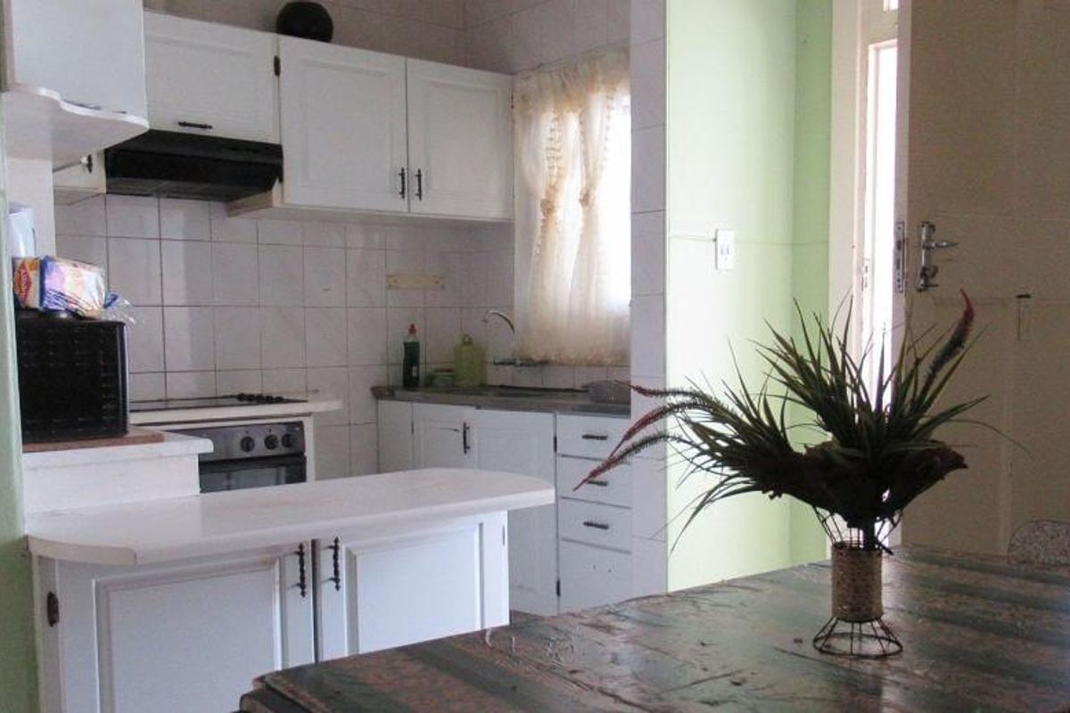 A functional kitchen featuring white cabinetry, a built-in oven and stove, tiled backsplash, and a compact breakfast counter.