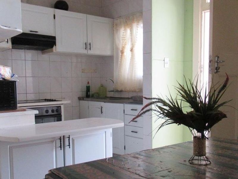 A functional kitchen featuring white cabinetry, a built-in oven and stove, tiled backsplash, and a compact breakfast counter.