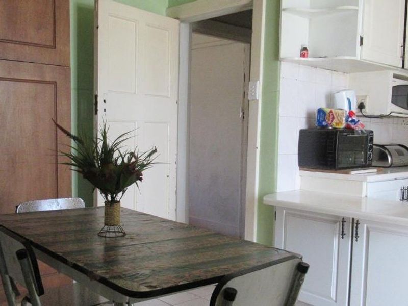 A dated kitchen featuring white cabinetry, tiled backsplash, and built-in appliances, offering potential for a modern renovation.