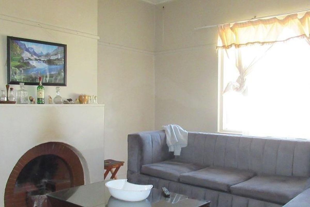 A living room featuring a traditional brick fireplace with a mantelpiece and a large window allowing natural light into the space.