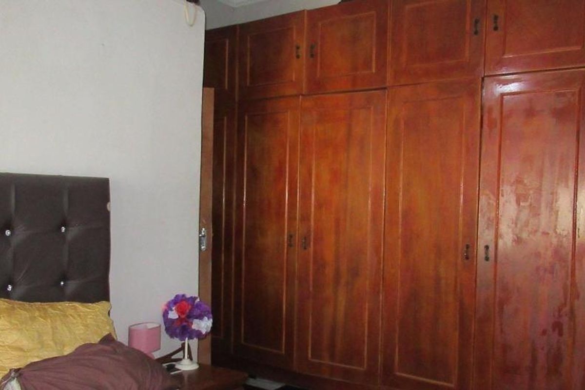 A bedroom featuring a large, full-height built-in wooden wardrobe with multiple storage compartments.