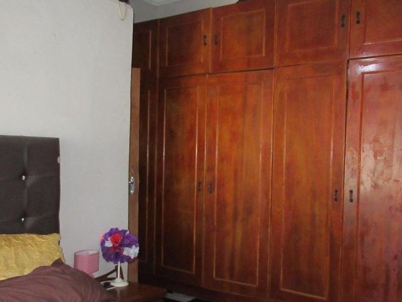 A bedroom featuring a large, full-height built-in wooden wardrobe with multiple storage compartments.