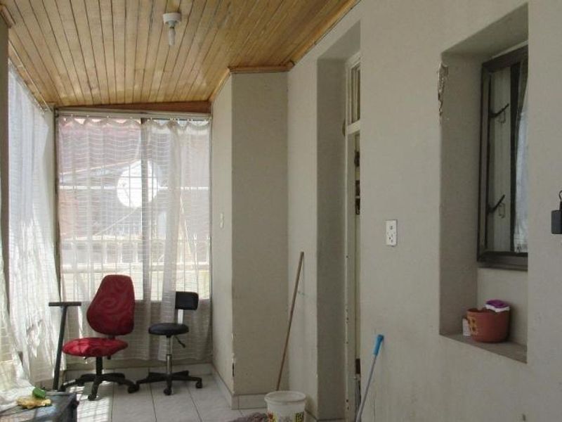 Enclosed patio area featuring a timber ceiling, tiled flooring, and large windows, offering a versatile space that could be updated for modern living.
