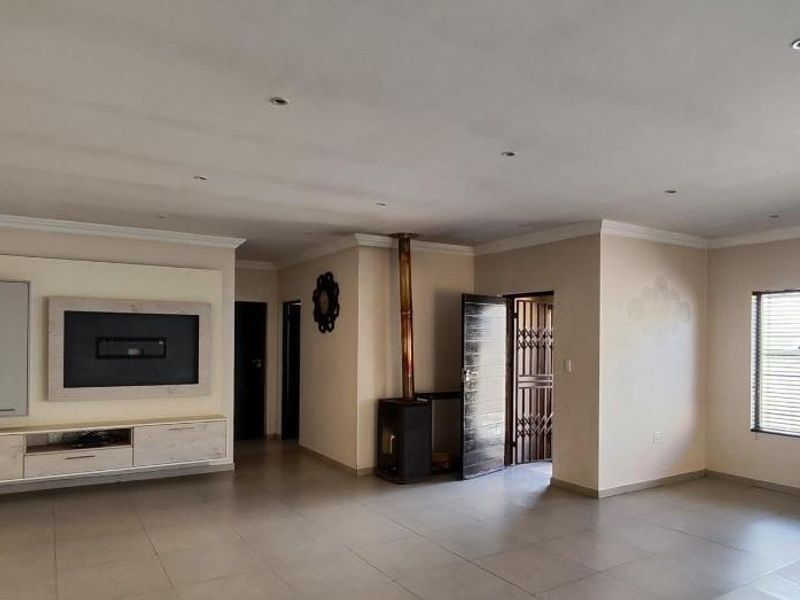 Spacious living area featuring tiled flooring, recessed lighting, a built-in media console, and a freestanding fireplace, offering a clean and versatile layout.