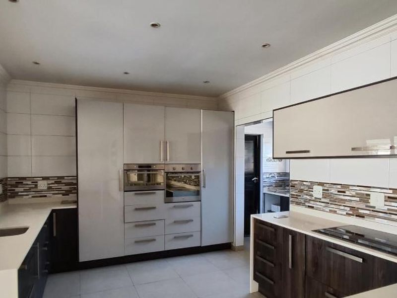 Modern kitchen featuring sleek cabinetry, built-in oven and microwave, induction hob, quartz countertops, and a stylish mosaic tiled backsplash.