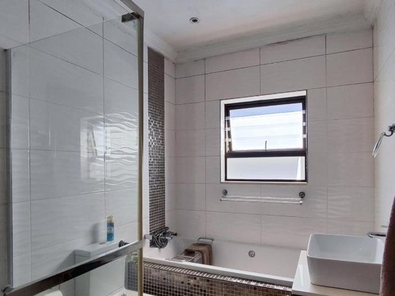 Modern bathroom featuring a glass-enclosed shower, built-in bathtub with mosaic tile accents, and a contemporary vessel sink.