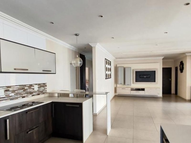 Spacious open-plan living area featuring a modern kitchen with stone countertops, a built-in media unit, and a cozy wood-burning fireplace.